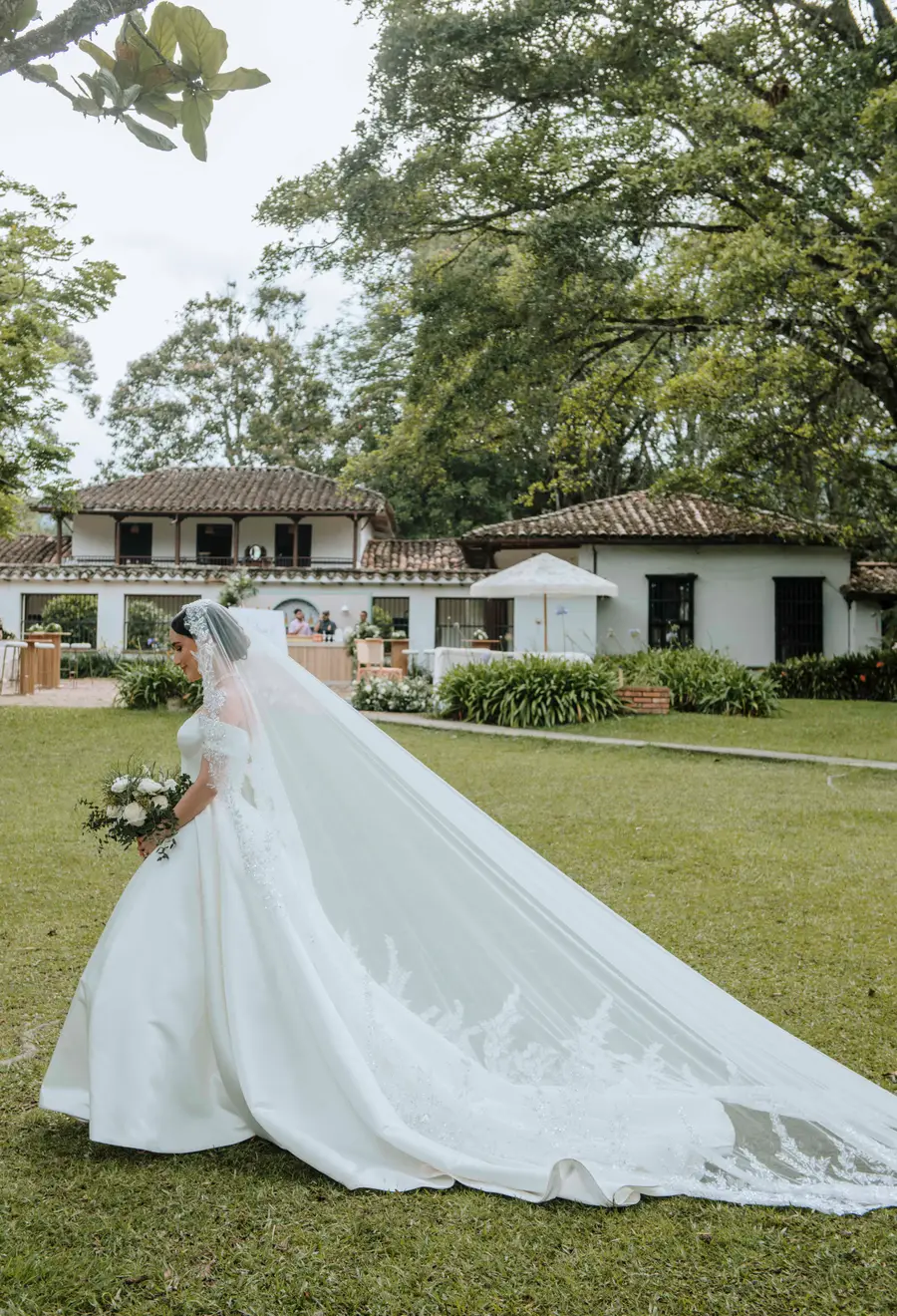 Bride walking through a garden with her veil extended