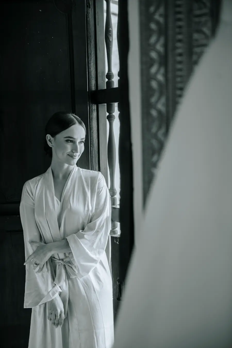 Black-and-white portrait of a bride by a window