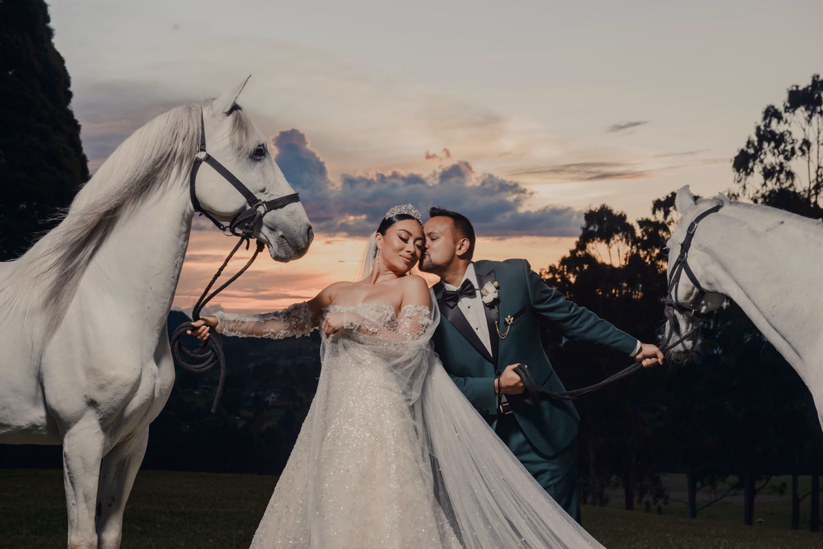 Pareja de recién casados junto a caballos blancos al atardecer