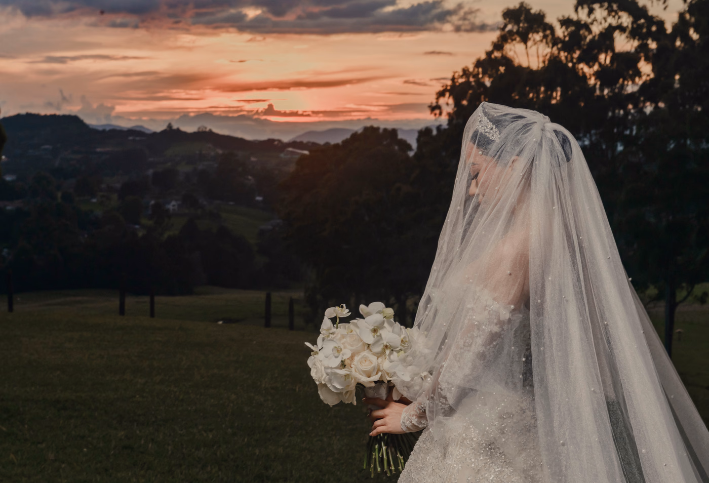 Novia bajo el velo frente a un atardecer en las montañas